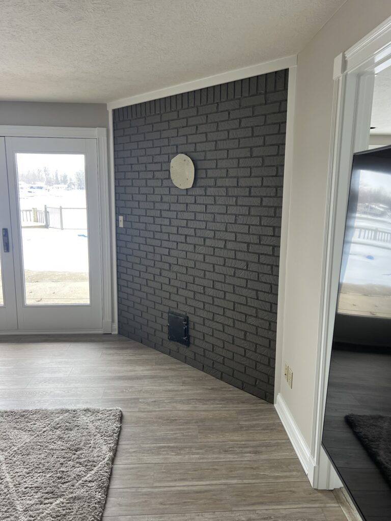Charcoal gray painted interior brick accent wall with white trim by Heritage Painting