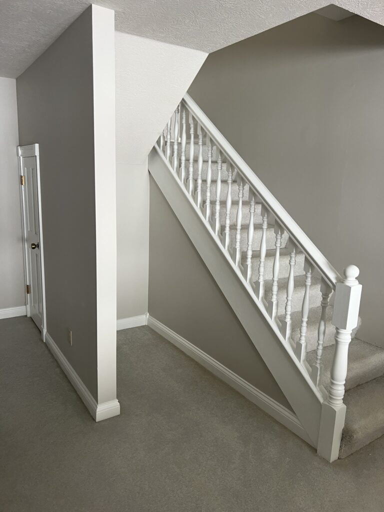 Staircase with gray walls and freshly painted white trim and balusters by Heritage Painting